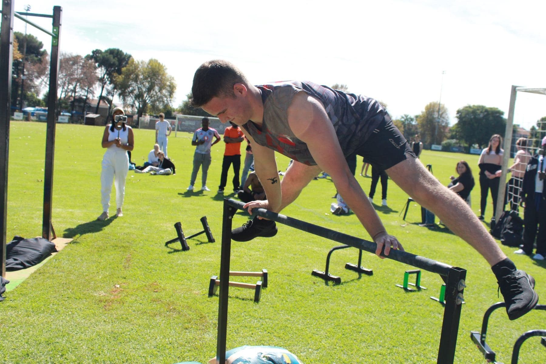 A competitor holding a front lever on the high bar against a bright sky at Freestyle Nationals.