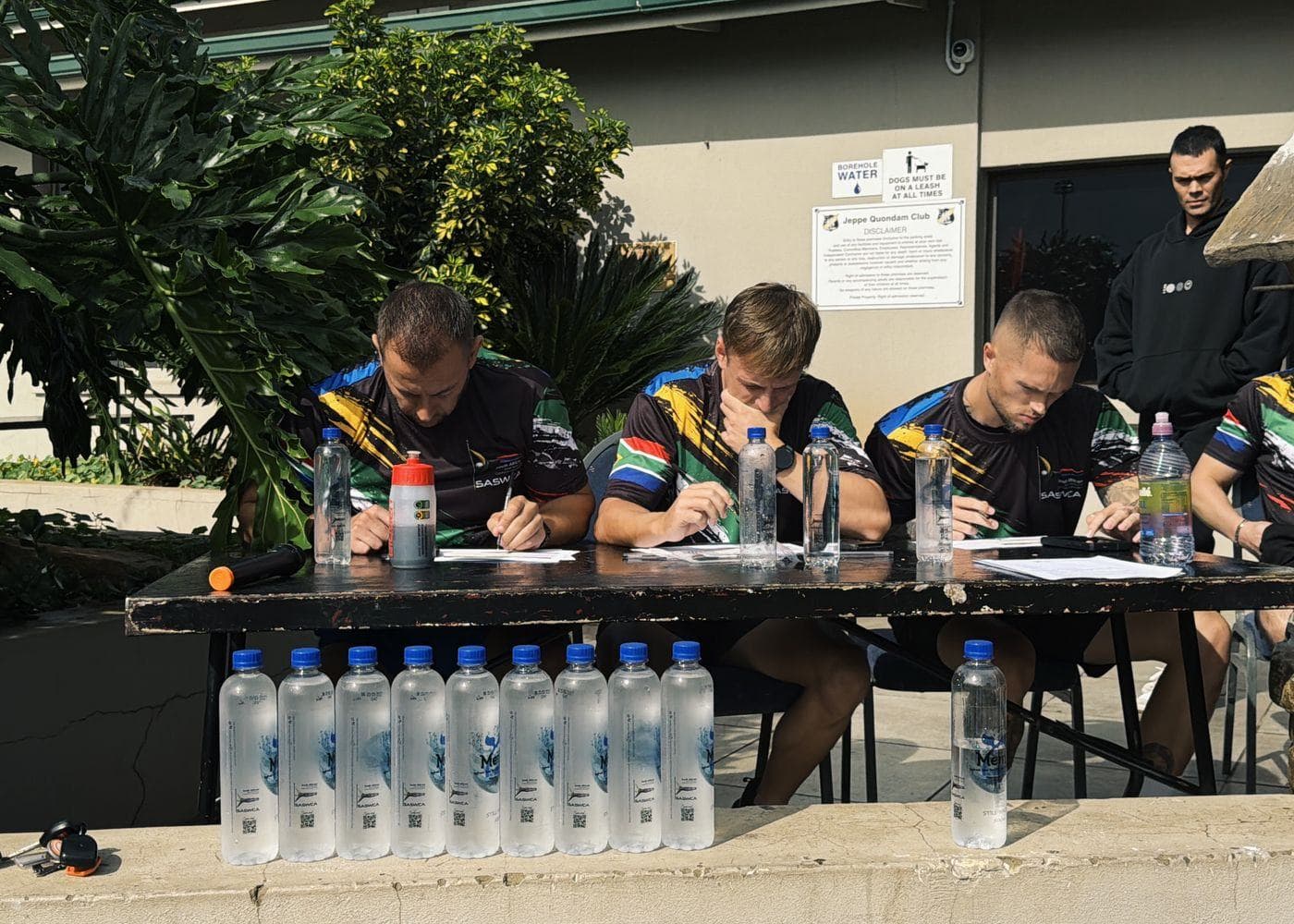 Three SASWCA judges in South African flag jerseys scoring at a table during a national competition.