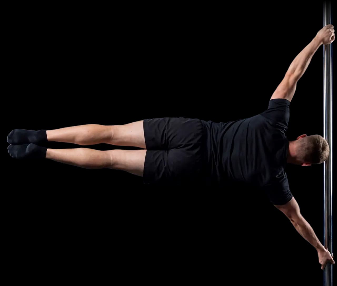 An athlete upside down on a chrome pole lowers both straight legs until his body is level in a human flag.